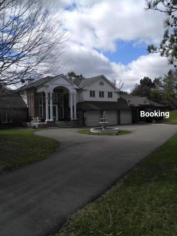 a large white house with a driveway at Lakeview private suite with kitchen-Twin or king in Tottenham