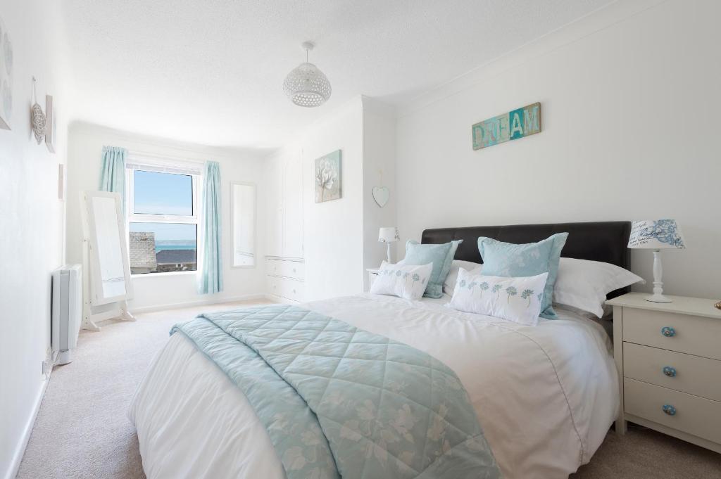 a white bedroom with a large bed and a window at Meledor in Marazion