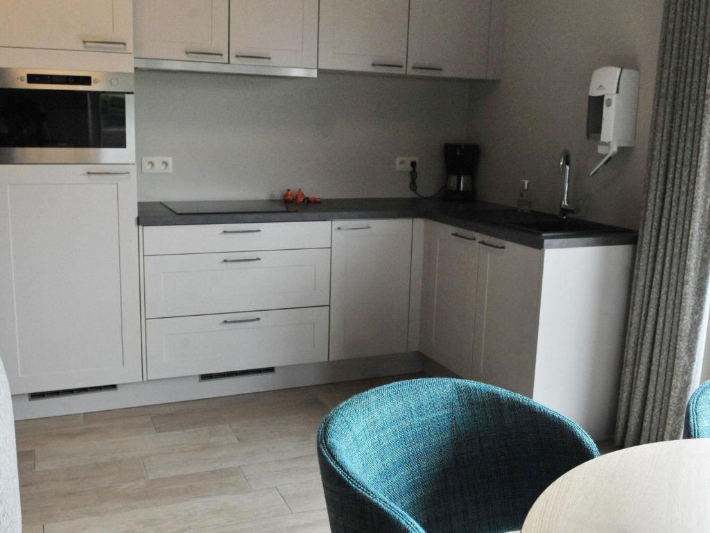 a kitchen with white cabinets and a blue chair at Splendid Holiday Home in Le Tignet South with Garden in Eisden