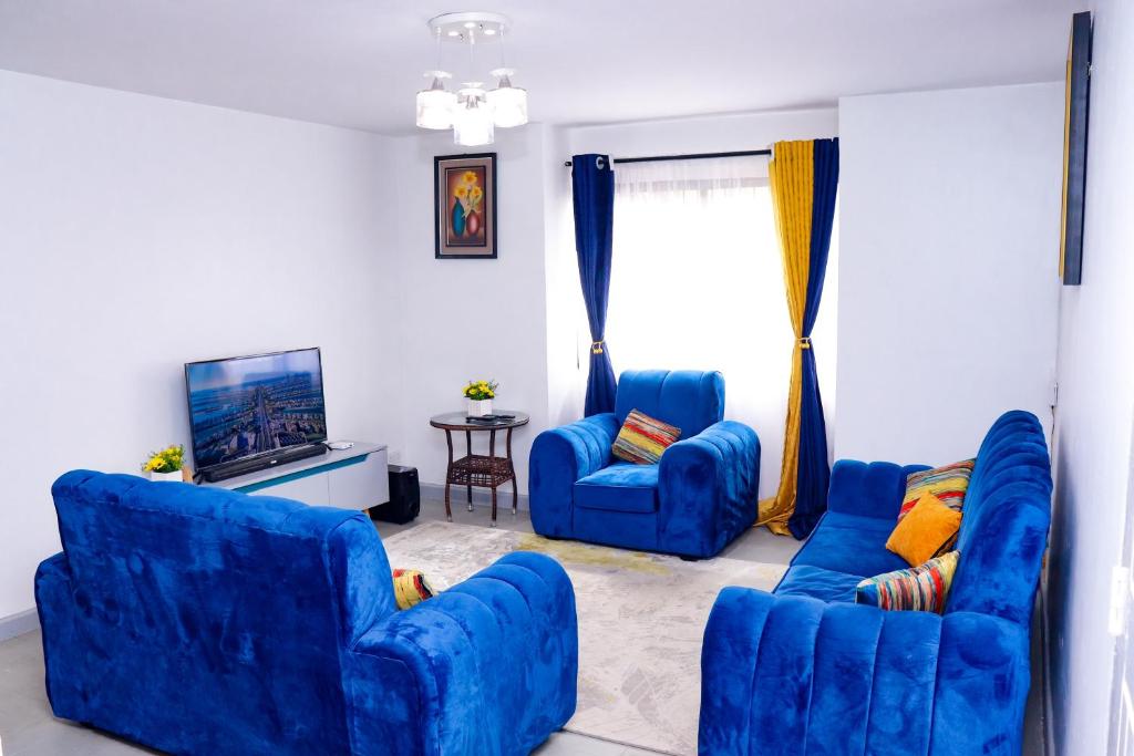 a living room with two blue chairs and a tv at Homely Homes in Nairobi