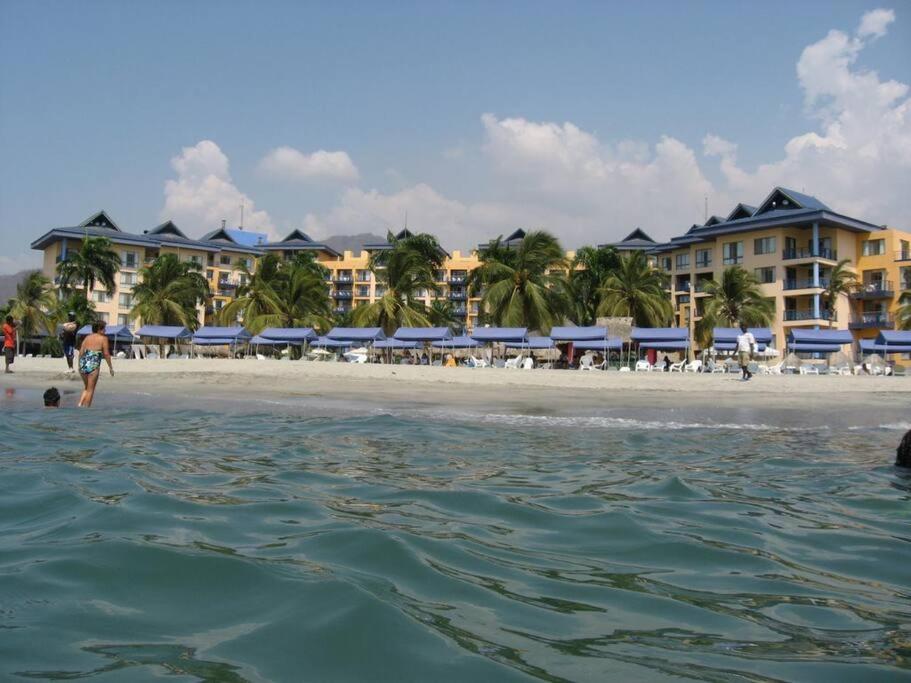 una spiaggia con un gruppo di hotel e persone in acqua di Hermoso apartamento. Cerca del mar. a Santa Marta