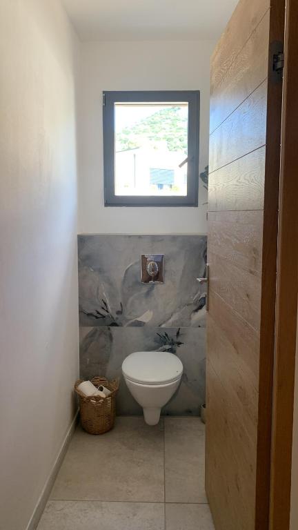 a bathroom with a toilet and a window at Maison neuve avec piscine in Corbara