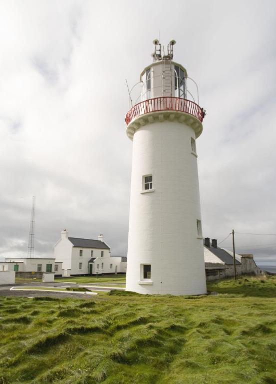 KilbahaLoop Head Lightkeeper's House的一座白色的灯塔,位于草地上