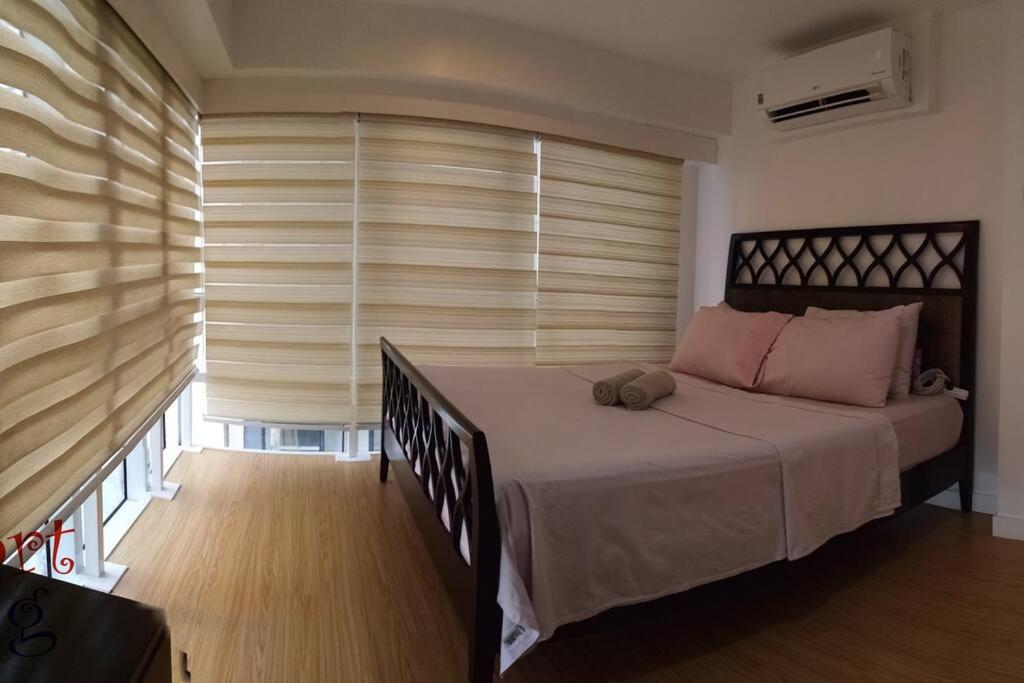a bedroom with a bed and a window with blinds at 2 BR loft-type condo Fort Victoria in Manila