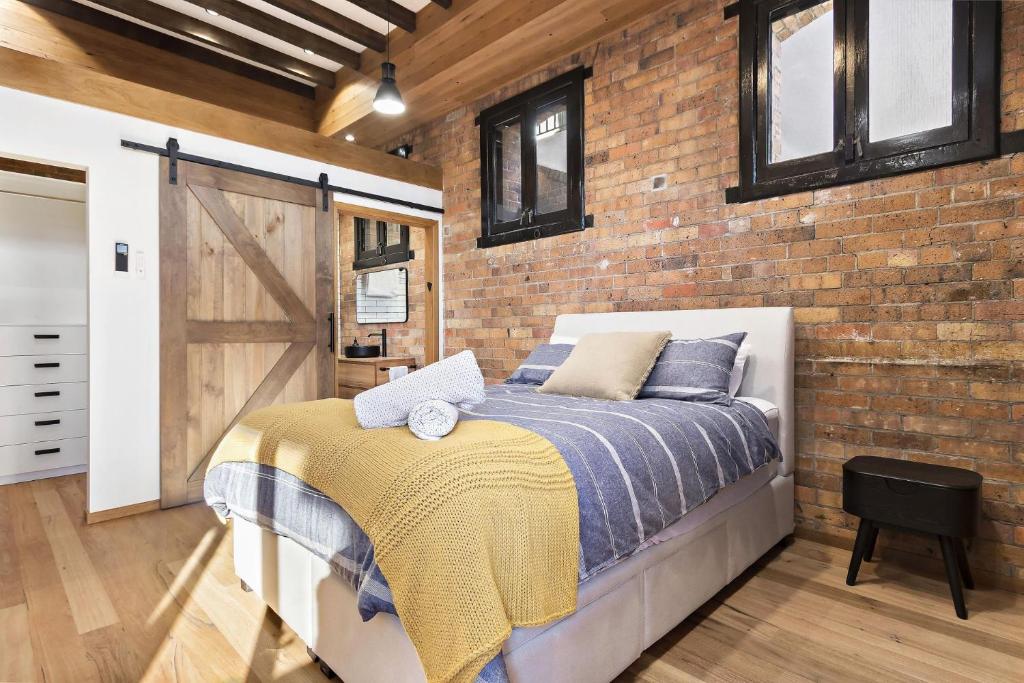 1 dormitorio con cama y pared de ladrillo en The Stables at the Hill, en Newcastle