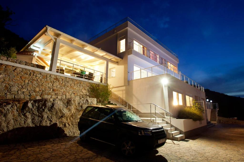 ein Auto, das nachts vor einem Haus parkt in der Unterkunft Luxury villa with a swimming pool Vis - 8922 in Vis