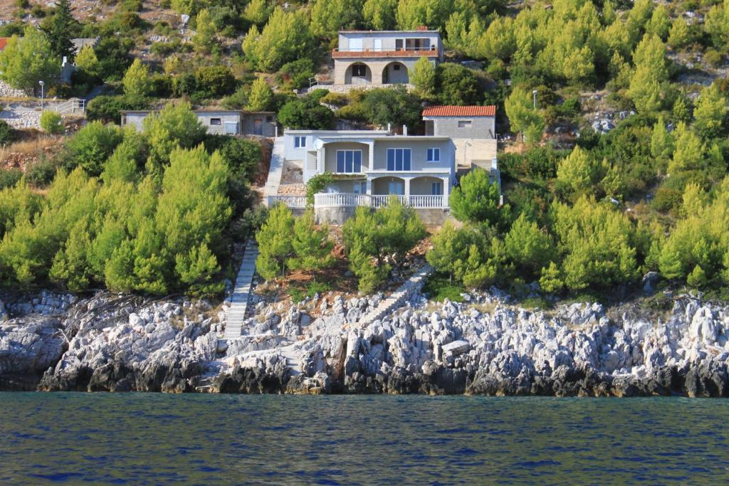 a house on a cliff next to the water at Apartments by the sea Brna - Vinacac, Korcula - 9152 in Smokvica