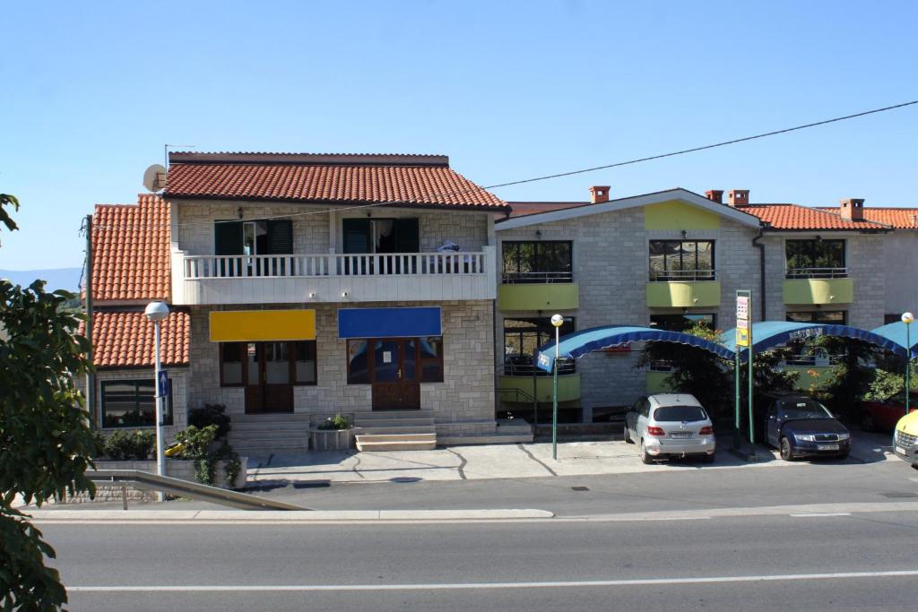 budynek z samochodami zaparkowanymi na parkingu w obiekcie Apartments and rooms with parking space Makarska - 9128 w Makarskiej