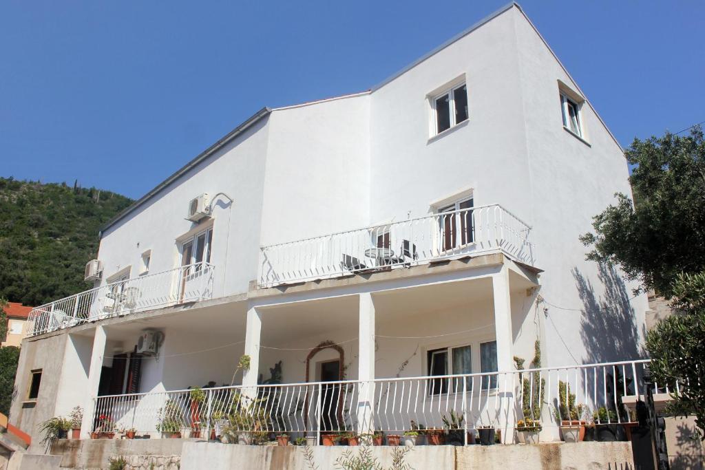 a white building with balconies and trees at Rooms with a parking space Zaton Mali (Dubrovnik) - 9114 in Zaton