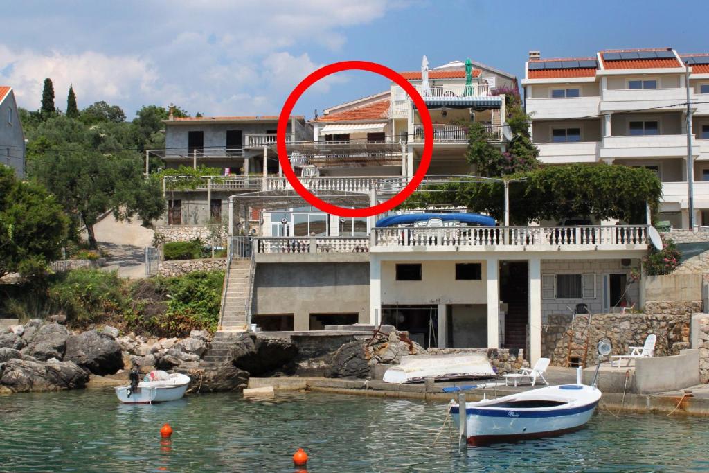 un cercle rouge sur un bâtiment avec des bateaux dans l'eau dans l'établissement Apartments and rooms by the sea Molunat, Dubrovnik - 8964, à Gruda