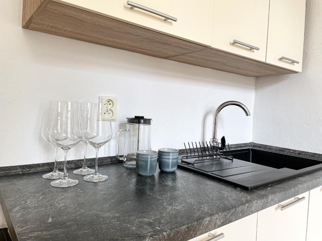 a kitchen counter with wine glasses and a sink at Arch Apartment in Třebíč in Třebíč