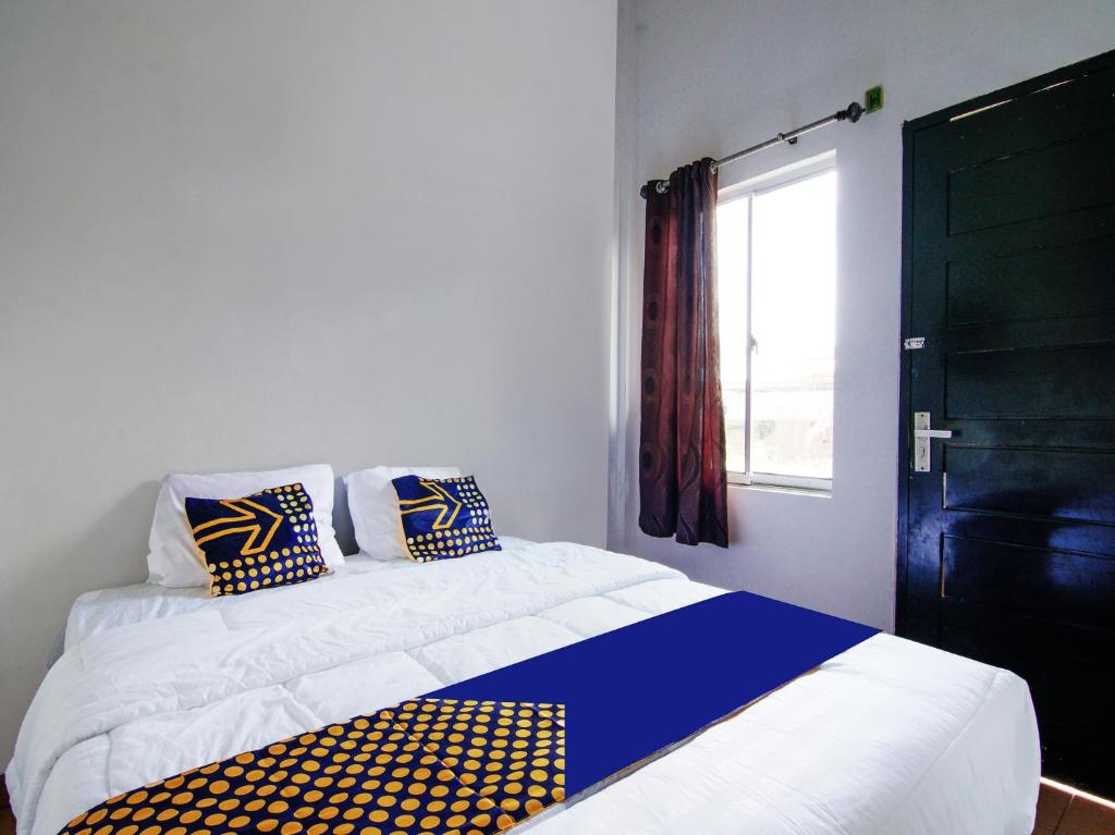 um quarto com uma cama com almofadas azuis e amarelas em SPOT ON 91598 Oklahoma Homestay Syariah em Pekanbaru