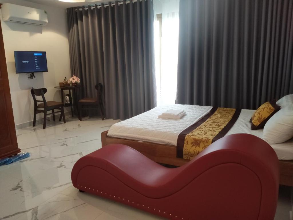 1 dormitorio con 2 camas y un banco rojo. en Khách sạn KEN HOTEL DĨ AN en Dĩ An
