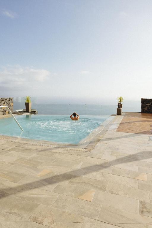 a person in a swimming pool with the ocean in the background at Anamcara Suites in Las Indias