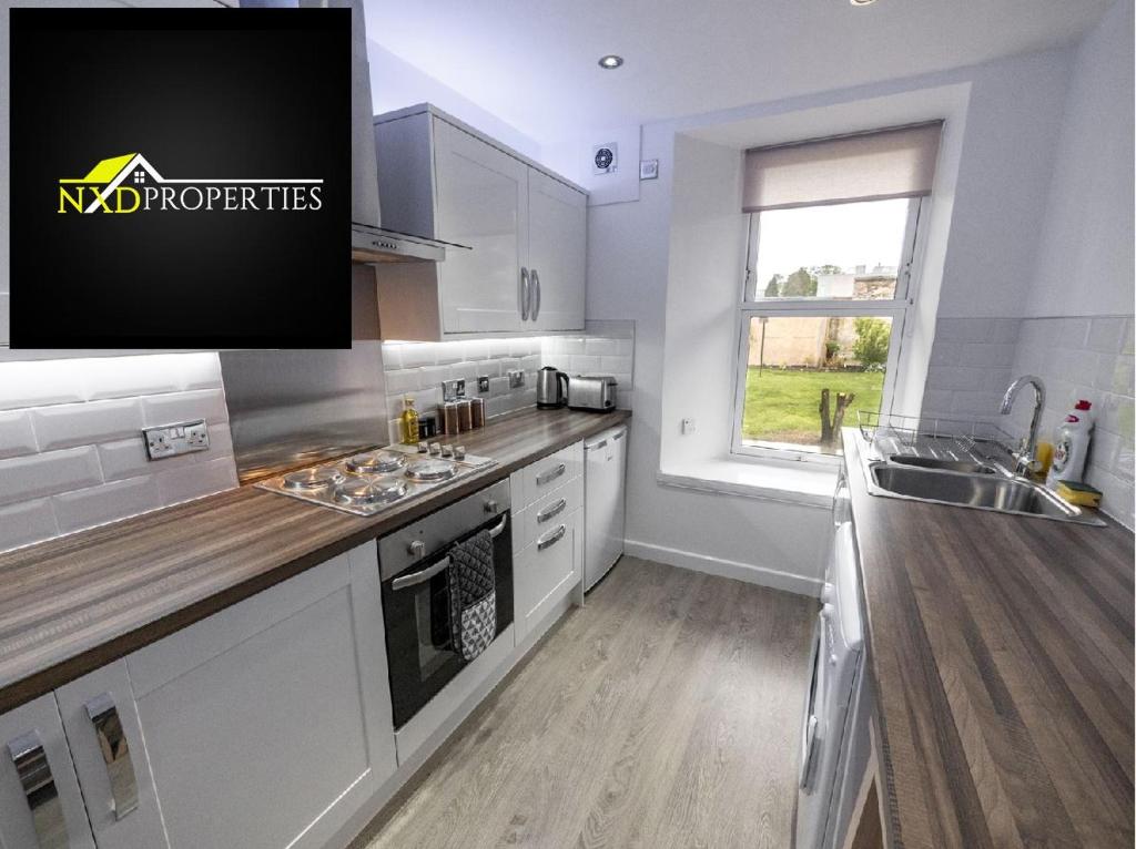 a kitchen with white cabinets and a sink and a window at ☆ New Superhost Listing- Broughty Ferry Studio ☆ in Broughty Ferry