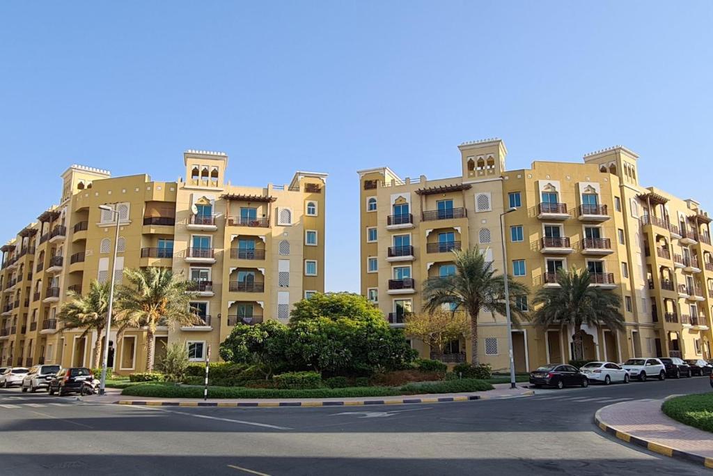 a large apartment building with cars parked in a parking lot at Cozy 1BR Apartment close to Dragon Market and Global Village in Dubai