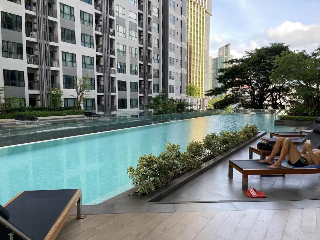 a woman laying on a bench next to a swimming pool at The Base Condo in Pattaya