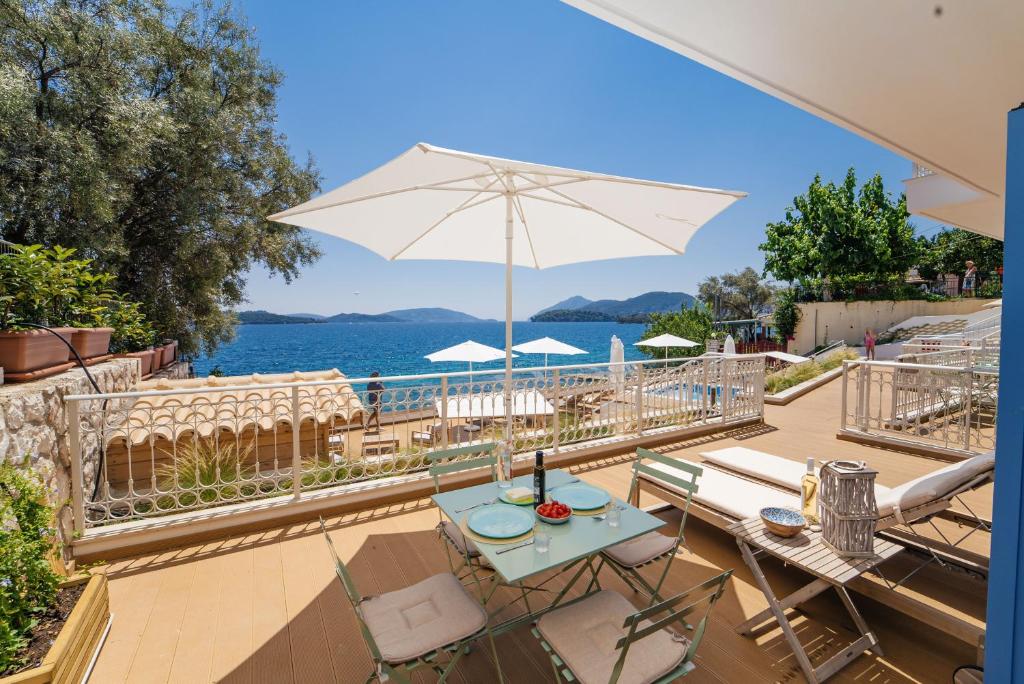 a patio with a table and chairs and an umbrella at Greek Beach House B2 Lefkada in Nydri