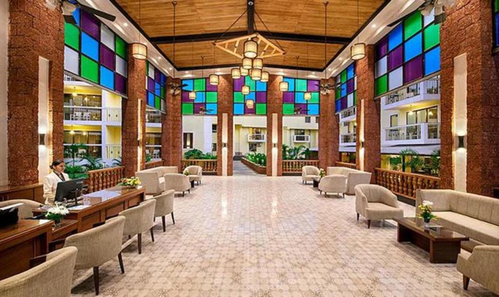 a lobby with chairs and tables and stained glass windows at Sea Breeze Max in Varca