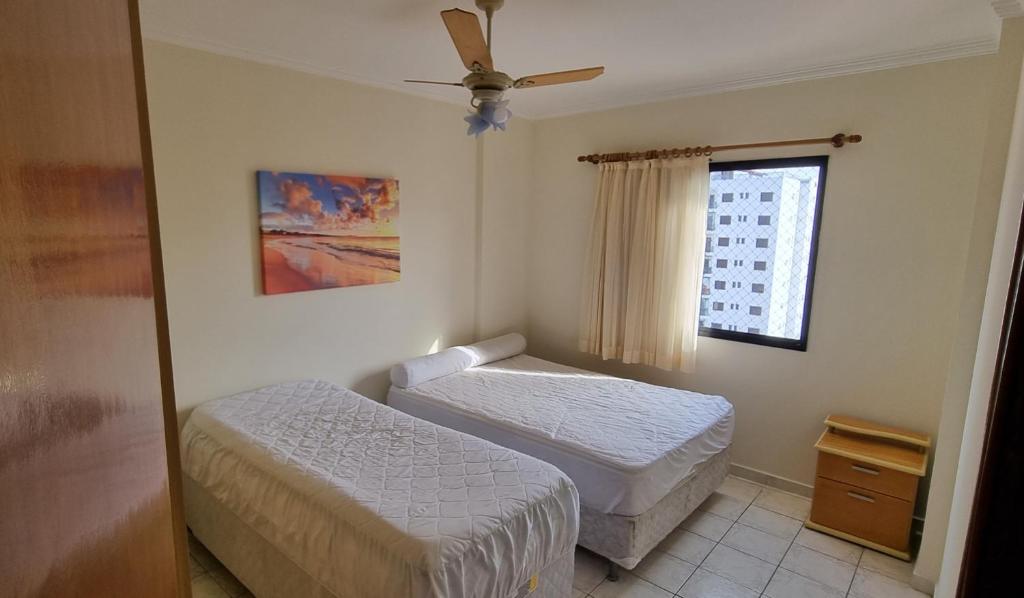 a bedroom with two beds and a window at Apartamento Praia Grande na Tupi Frente Mar in Praia Grande