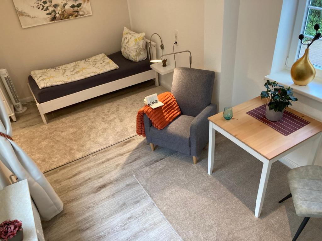 ein Wohnzimmer mit einem Bett, einem Stuhl und einem Tisch in der Unterkunft Gästehaus Langhals in Bad Segeberg
