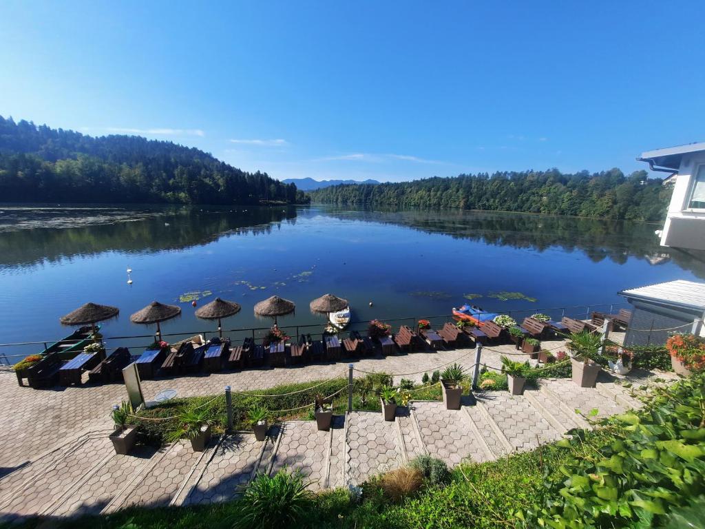 vistas a un río con mesas y sombrillas en Gostisce Jezero, en Medvode