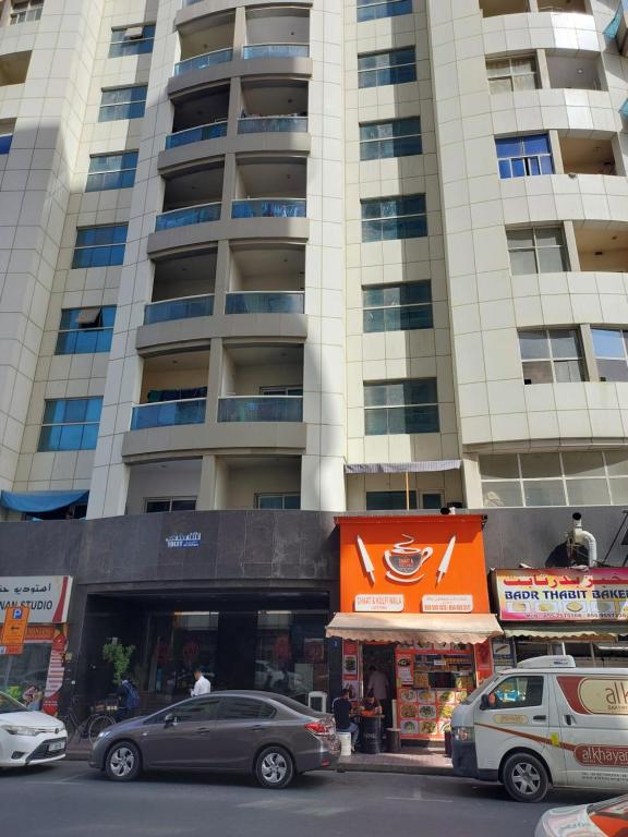 a tall building with cars parked in front of it at GRACE BEDSPACE, HOSTEL AND ACCOMODATIONS in Dubai