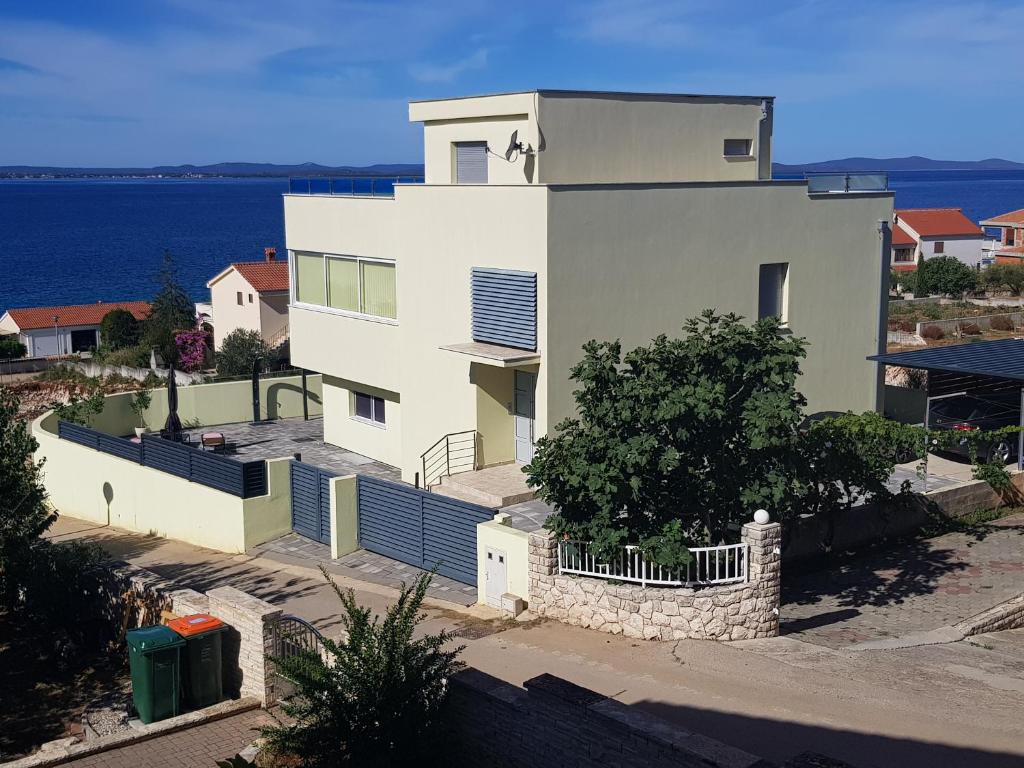 a white house with the ocean in the background at Yellow Cube in Kožino