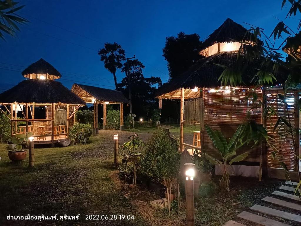 a group of huts with lights at night at สวนเกษตรรักษ์ไผ่ Bamboo Conservation Farm in Surin