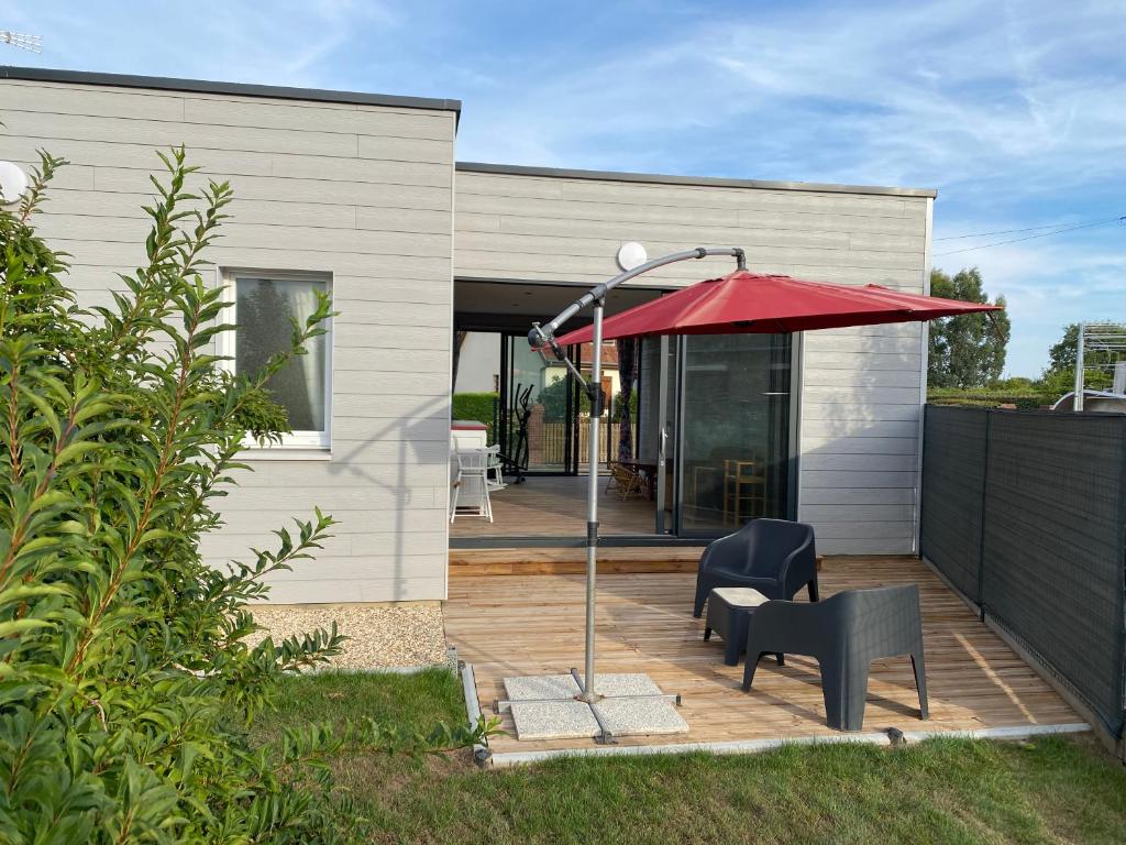 un patio con una sombrilla roja, una silla y una mesa en Gîte proche de Dieppe et bord de mer, en Petit-Berneval