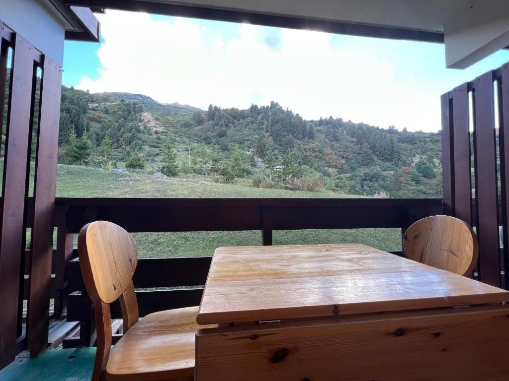 d'une table et de chaises en bois sur un balcon avec vue. dans l'établissement Appart 4personnes - Pied des pistes - Sud - Mottaret, à Les Allues