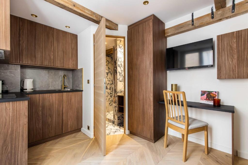 a kitchen with wooden cabinets and a chair in a room at CMG- Charming appartement 2P - Batignolles in Paris