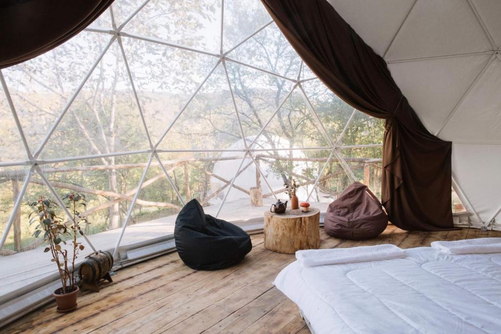 a room with a bed and a large glass window at Elsesi Racha Glamping in Ambrolauri