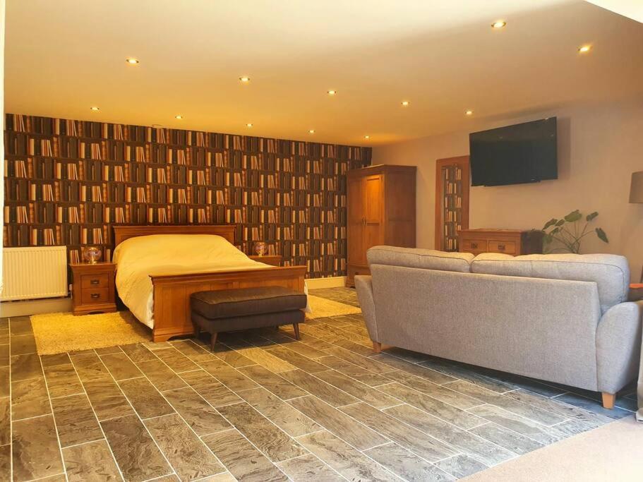 a bedroom with a bed and a couch and a tv at Sycamore Suite is a private retreat with log fire in Eckington