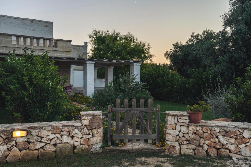 a house with a stone fence and a wooden bench at Masseria della Piana in Villanova di Ostuni