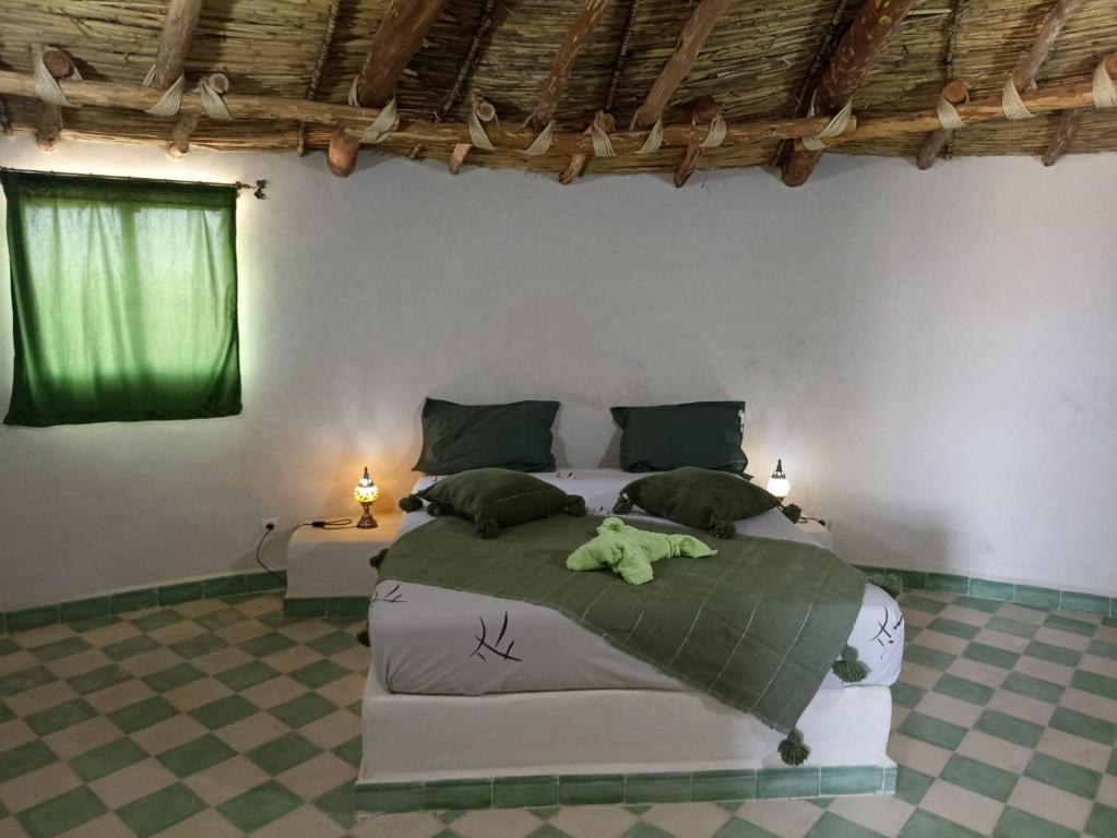 a bedroom with a bed with a green stuffed animal on it at Les Jardins d Amizmiz in Marrakech