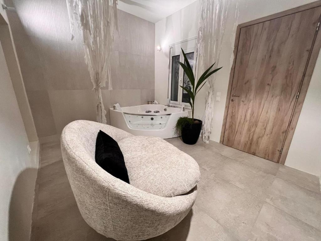 La salle de bains est pourvue d'une chaise blanche avec un oreiller noir. dans l'établissement Perla Coco Jacuzzi Suites, à La Canée