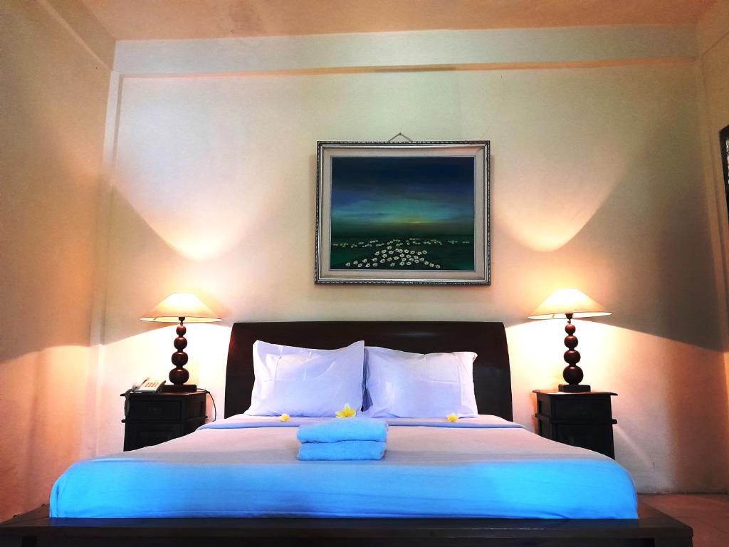 a bedroom with a large bed with two lamps at Panorama Hotel in Ubud