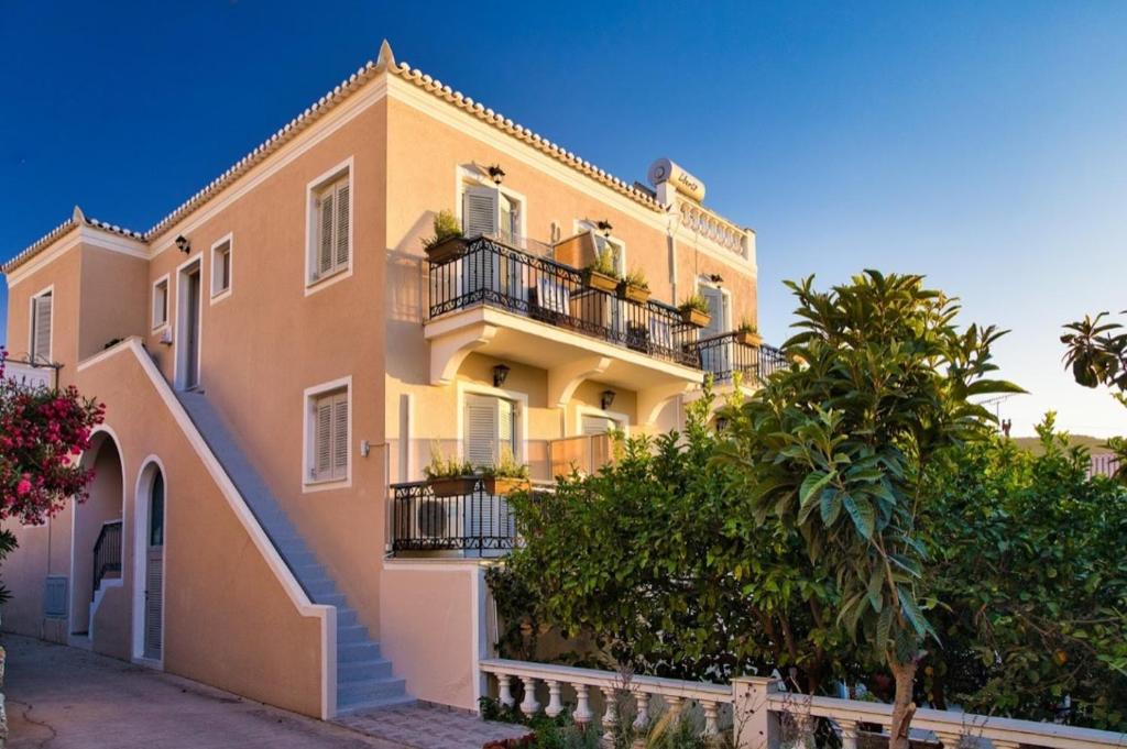 a large yellow building with balconies and trees at Argonaftis Spetses in Spetses