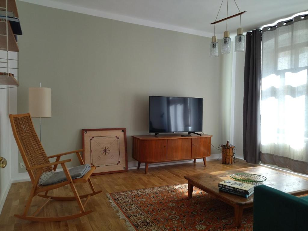 ein Wohnzimmer mit einem TV, einem Stuhl und einem Tisch in der Unterkunft Ferienwohnung im Süden in Görlitz