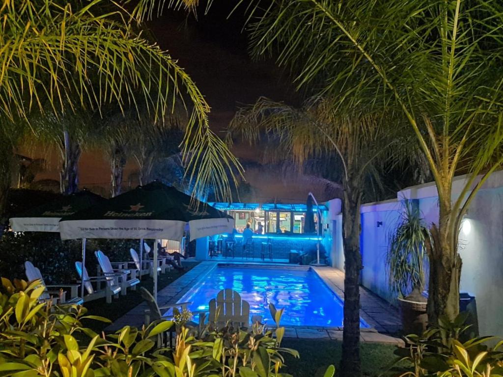 a swimming pool at night with palm trees at Palm Valley Inn in Hartbeespoort