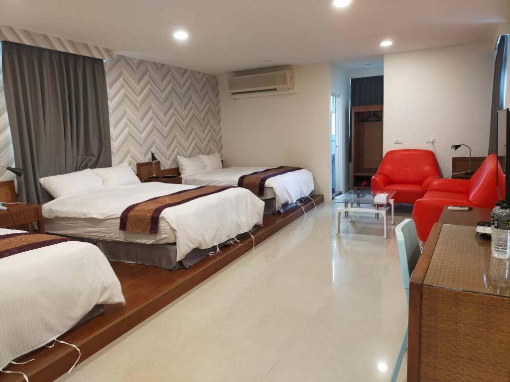 a hotel room with two beds and a red chair at Hai Gang Yuan Homestay in Kenting
