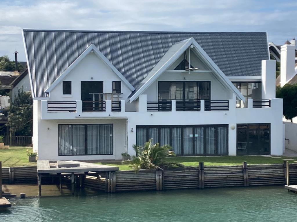 una casa blanca en el agua con muelle en St Francis Bay House On The Canal, en St Francis Bay