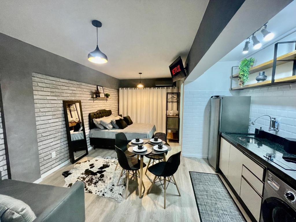 eine Küche und ein Wohnzimmer mit einem Tisch im Zimmer in der Unterkunft Studio 308 no Kobrasol à 7km de Floripa in São José