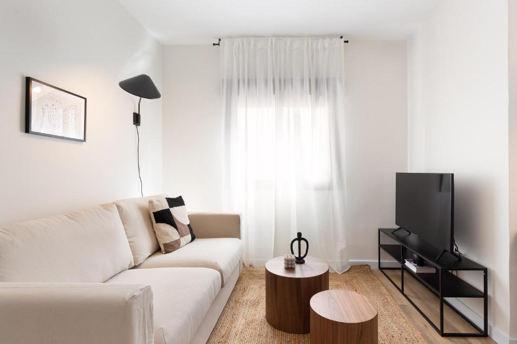 sala de estar con sofá blanco y TV en Urban Chill Apartments by Olala Homes, en Hospitalet de Llobregat