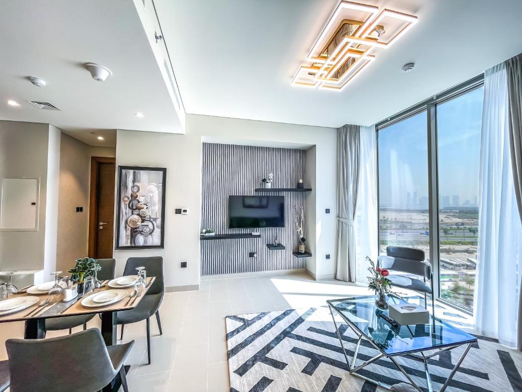 een woonkamer met een tafel en stoelen en een televisie bij STAY BY LATINEM 2BR Holiday Home CV B514 near Burj Khalifa in Dubai