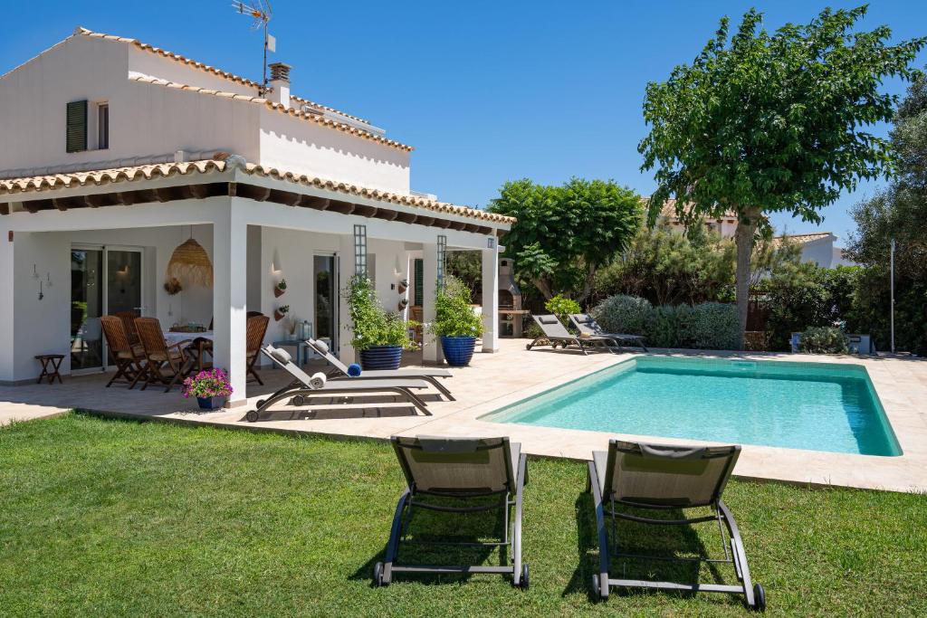 a villa with a swimming pool and two lawn chairs at Villa El Olivo Menorca in Binisafua