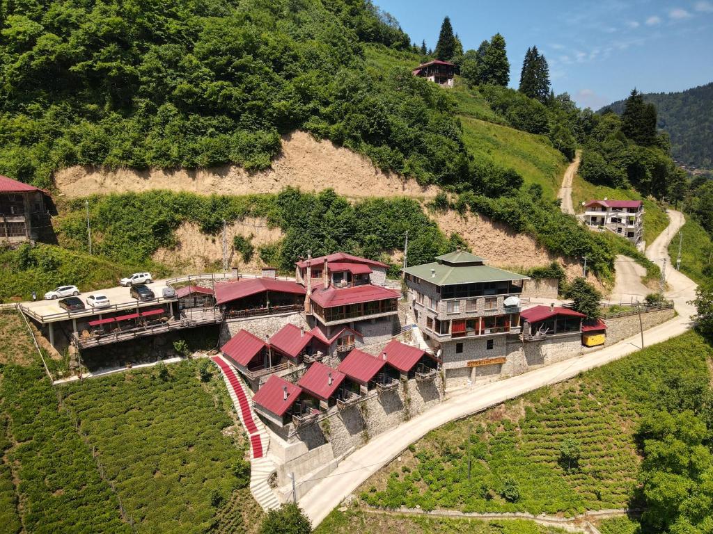 un bâtiment avec des toits rouges sur une colline avec un train dans l'établissement Seyr-i Cennet Dag Evleri, à Çamlıhemşin