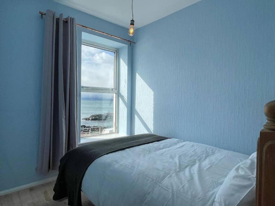 斯圖爾特港的住宿－The Nook, Portstewart，一间卧室设有一张床和一个海景窗户
