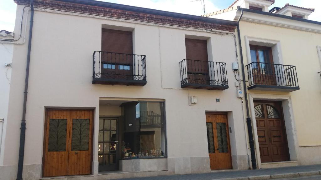 Edificio blanco con puertas de madera y balcón en La casa de El Burgo, en El Burgo de Osma